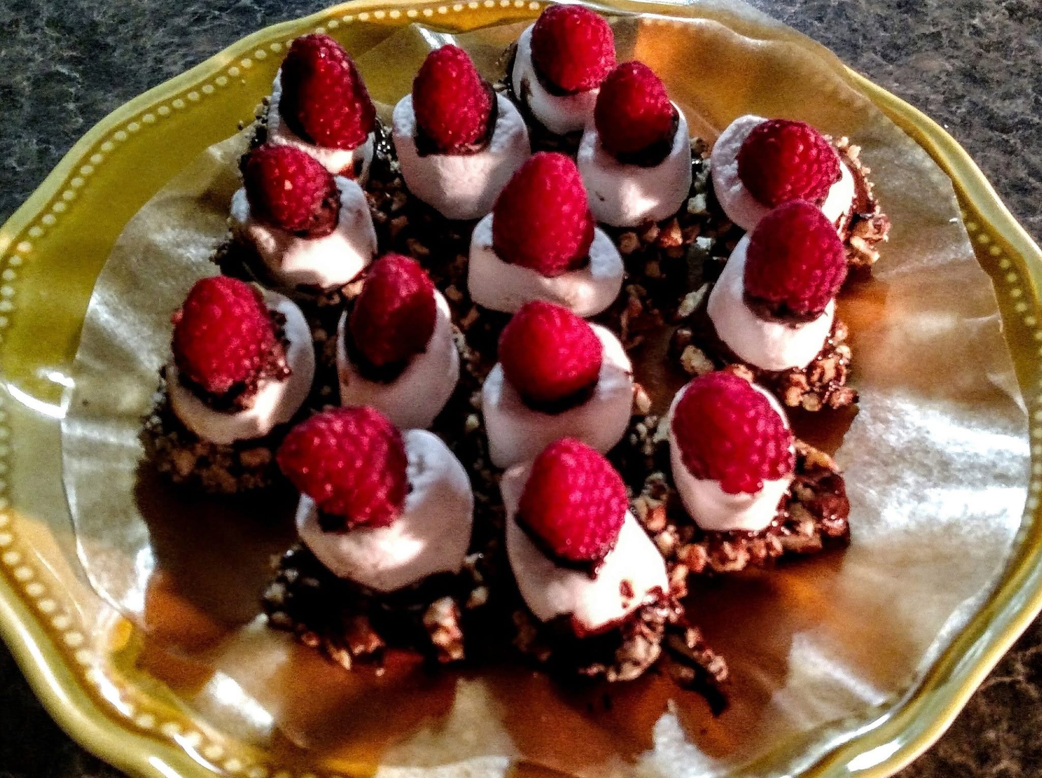 Dark chocolate dipped marshmallows rolled in crushed pecans a raspberry crown all atop dark chocolate